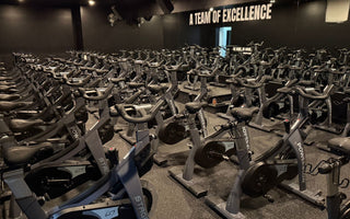 Large spin class fitness studio with rows of commercial indoor cycling bikes