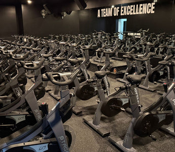 Large spin class fitness studio with rows of commercial indoor cycling bikes