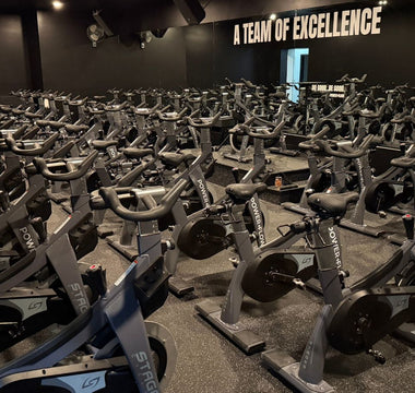 Large spin class fitness studio with rows of commercial indoor cycling bikes