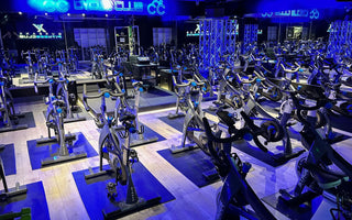 Spin studio with rows of commercial indoor cycling bikes prepared for group fitness classes