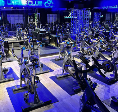 Spin studio with rows of commercial indoor cycling bikes prepared for group fitness classes