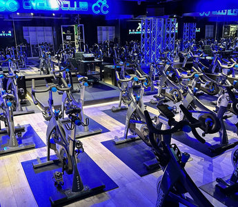 Stages indoor cycling bikes inside a busy commercial cycling studio