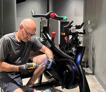 Indoor Cycle Pros technician Andrew Sandoval repairing a Stages SC2 indoor spin bike at a cycling studio