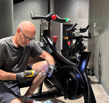 Indoor Cycle Pros technician Andrew Sandoval repairing a Stages SC2 indoor spin bike at a cycling studio
