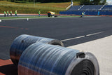 Rolls of REGUPOL abzorb shock pad with installed pad covering a stadium field